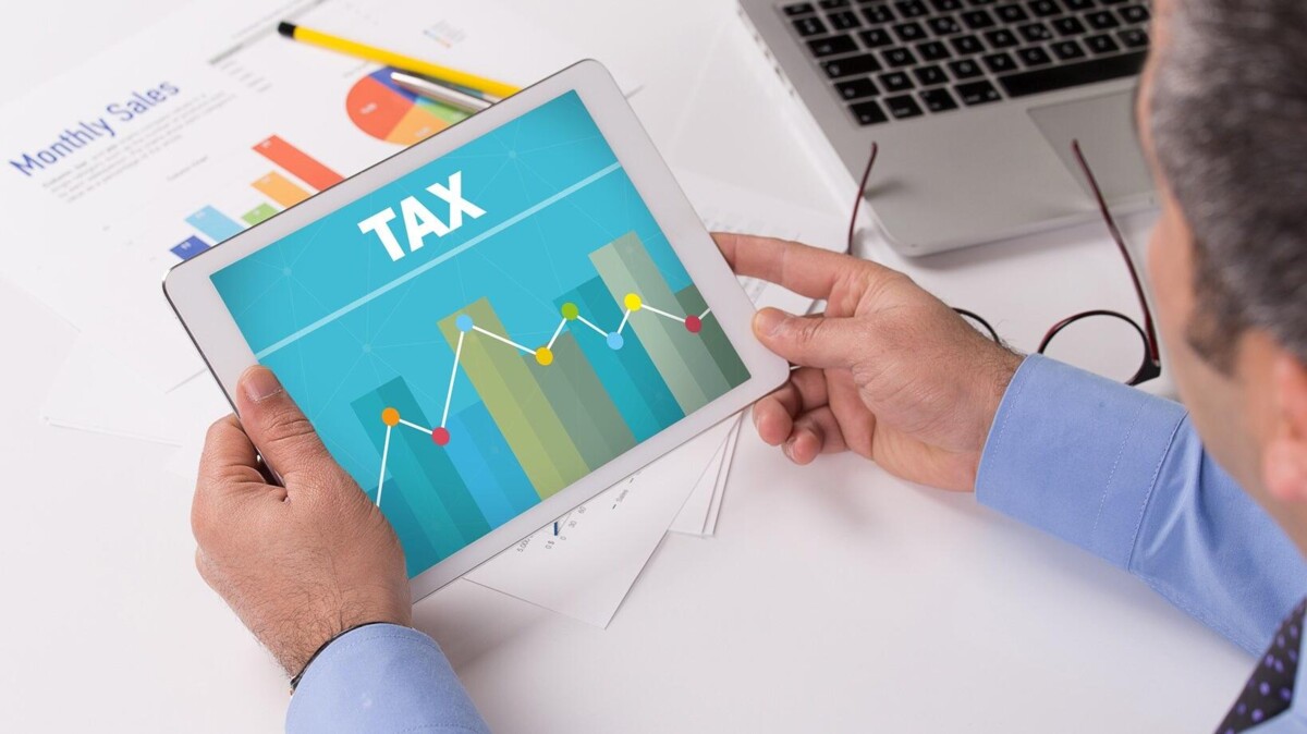 Belastingadviseur kijkt op tablet met text 'Tax'. 